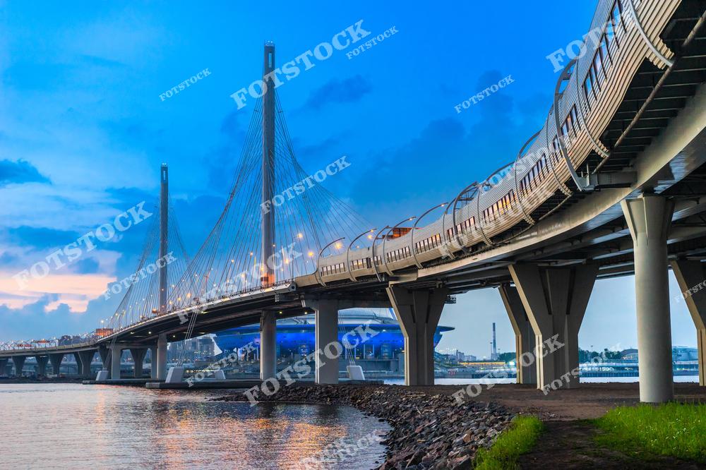 Фотография панорамного вида города Санкт-Петербург, выполненная с высоты птичьего полёта. На изображении показана современная городская инфраструктура: автомагистраль, мосты Петербурга и масштабная панорама мегаполиса. Фотоснимок передаёт динамику транспортных потоков и архитектурный облик города, включая Крестовский остров. Это изображение отражает концепцию панорамы российских городов, сочетая урбанистику, мостовые сооружения и прибрежные зоны. Иллюстрация может использоваться как картинка или слайд, посвящённые развитию и архитектуре Санкт-Петербурга.